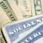 Close-up of a Social Security card partially covered by U.S. currency, featuring green and blue tones.