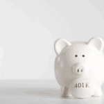 White piggy bank holding a coin labeled "401K," set against a plain white background.
