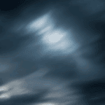Dark, swirling clouds with varying shades of gray and hints of light peeking through, creating a dramatic sky.