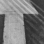 White arrow on a dark asphalt surface, showing signs of wear and tire marks around it.