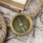 gold compass sitting on a map with a rope