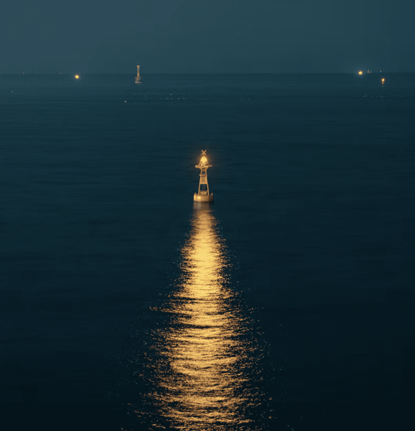Lone buoy with a bright light in the ocean at night, reflecting golden light on the water surface. Distant lights visible on the horizon.