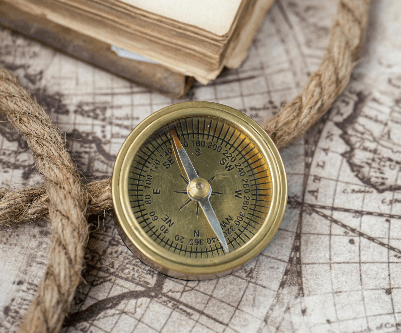 gold compass sitting on a map with a rope